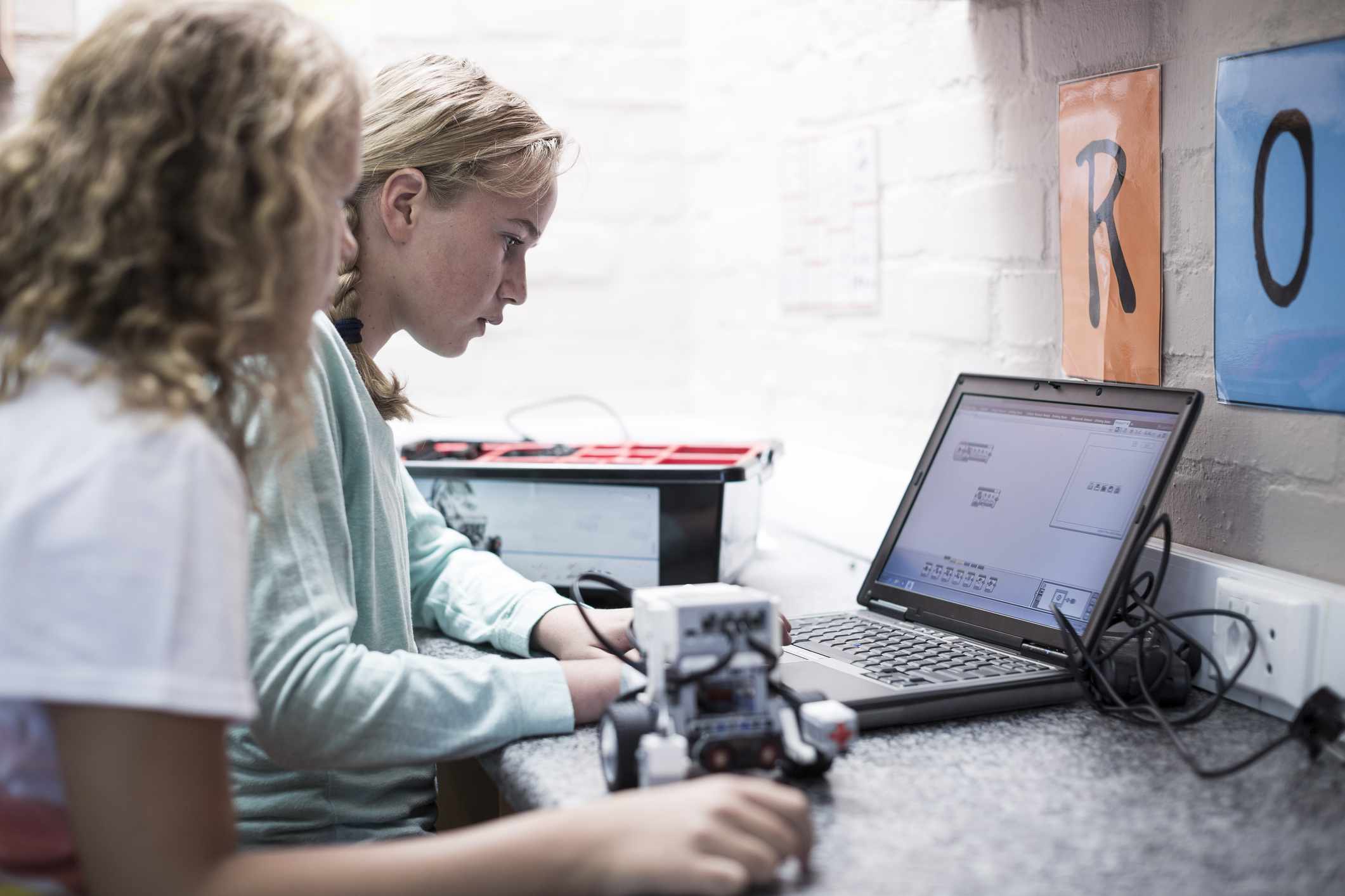 Opiskelija koodaa ohjelman robotille kannettavalla tietokoneella.