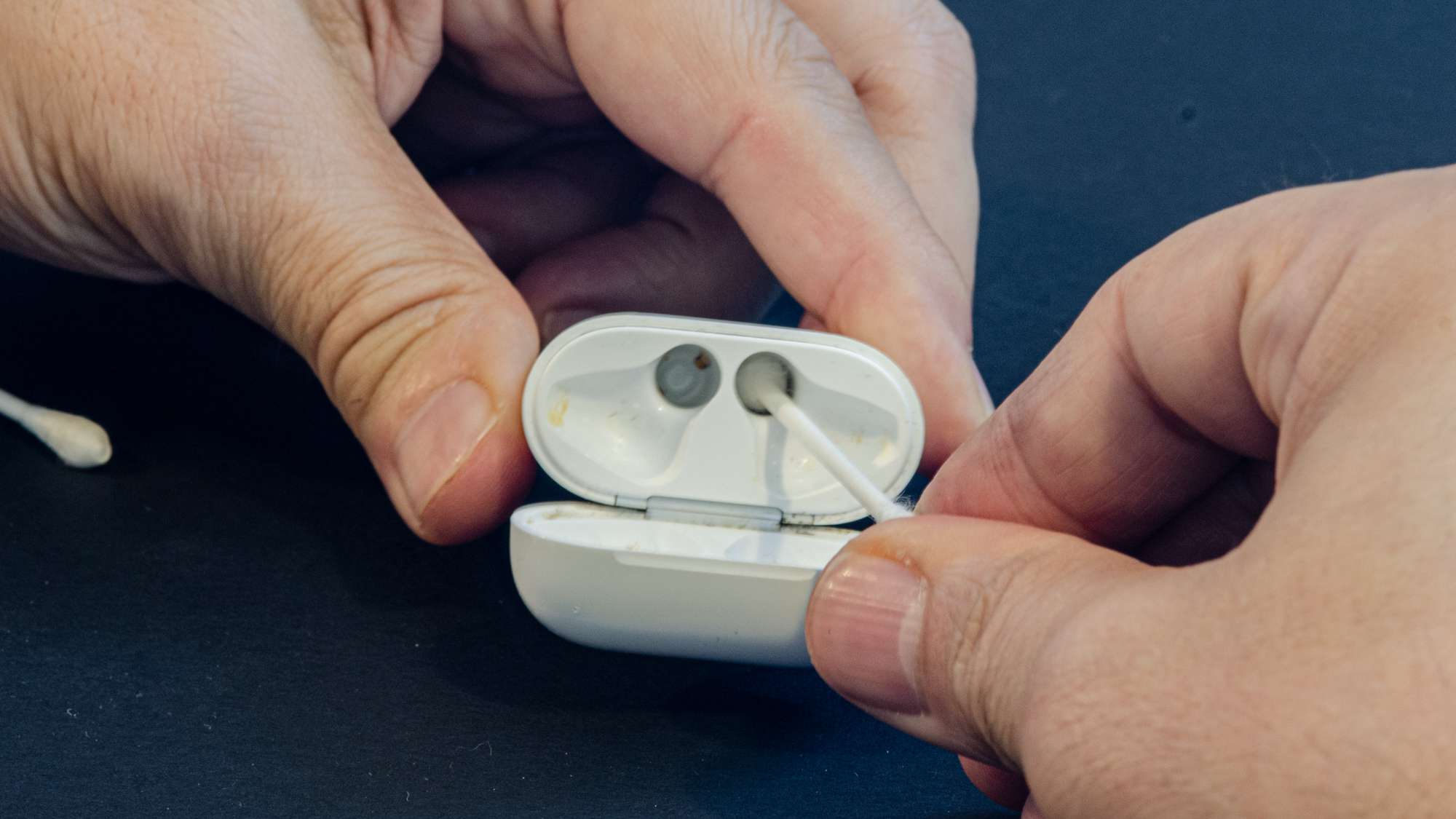 AirPods-kotelon varren puhdistaminen pumpulipuikolla.