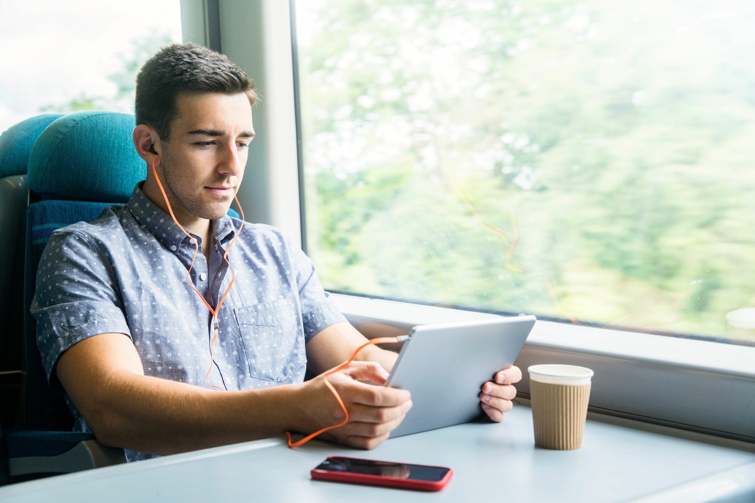 man with tablet and headphones on train 629639549 59c3f06422fa3a00118b0616 scaled