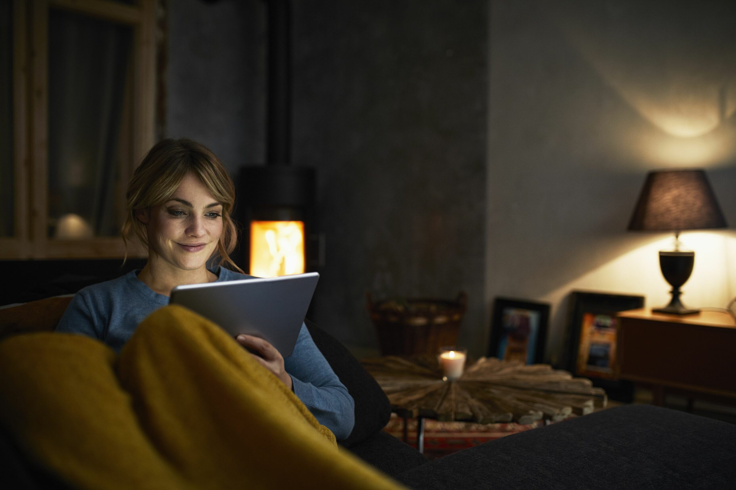 portrait of smiling woman with tablet relaxing on couch in the evening 919443026 5c0964a746e0fb00011af583 scaled