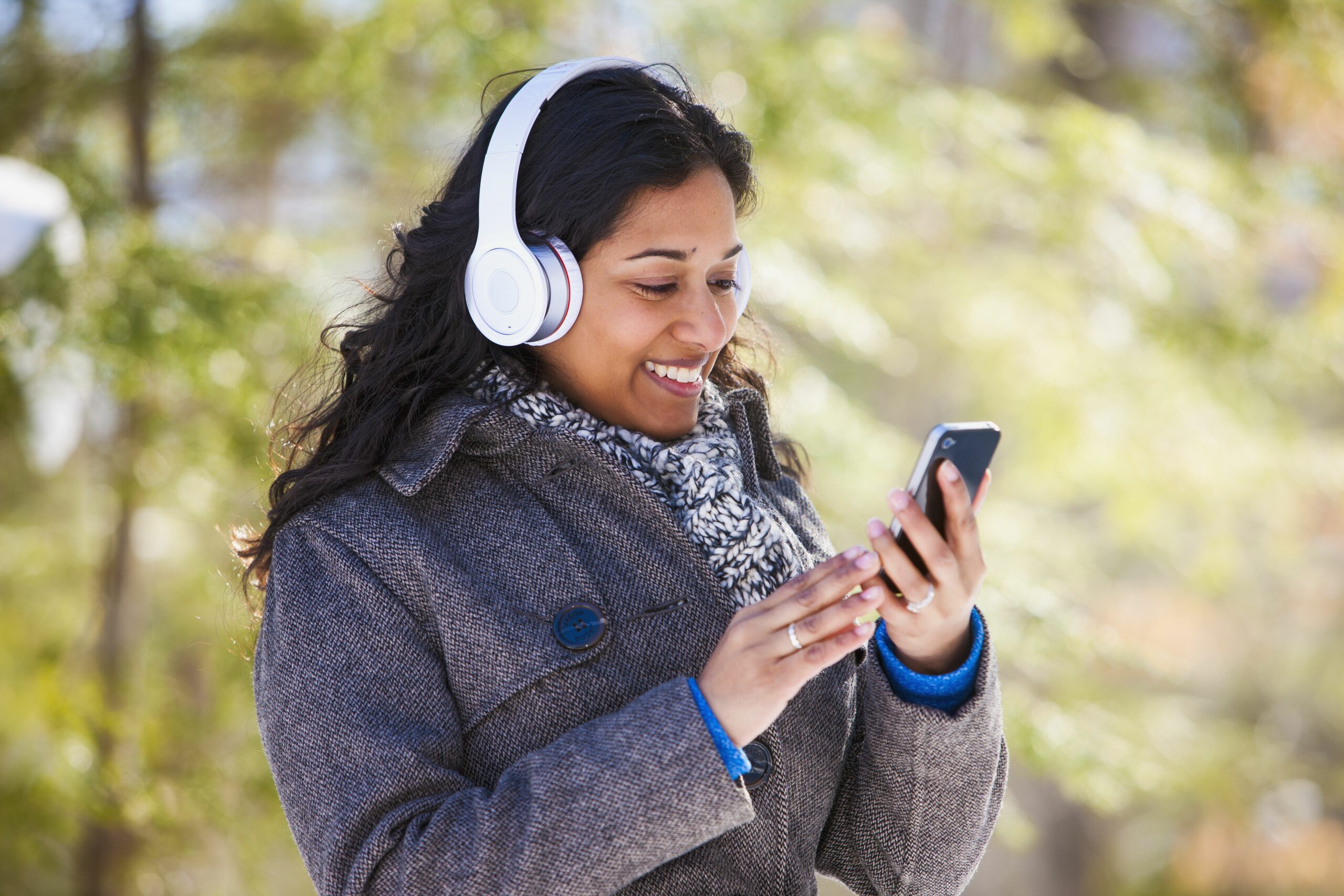 young woman of south asian ethnicity using cell phone and bluetooth headphones in scanlon creek conservation area 574897321 5aa1b50e18ba010037c50439 scaled