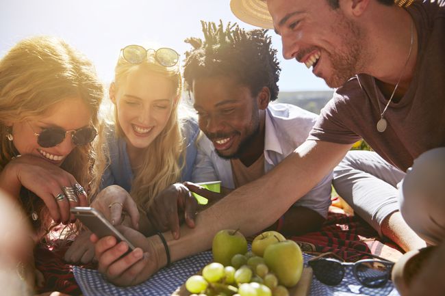 Ryhmä nauravia ystäviä kokoontui yhden iPhonen ympärille ja katseli sydämenlyöntejä