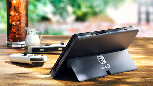 Nintendo Switch OLED -malli seisoo jalustalla valkoisten joy-con-ohjainten vieressä