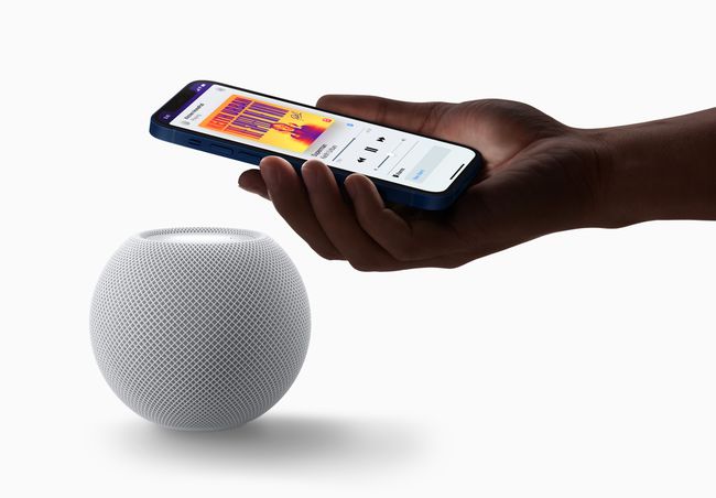 Lähikuva kädestä, joka pitää älypuhelinta HomePod Minin päällä.