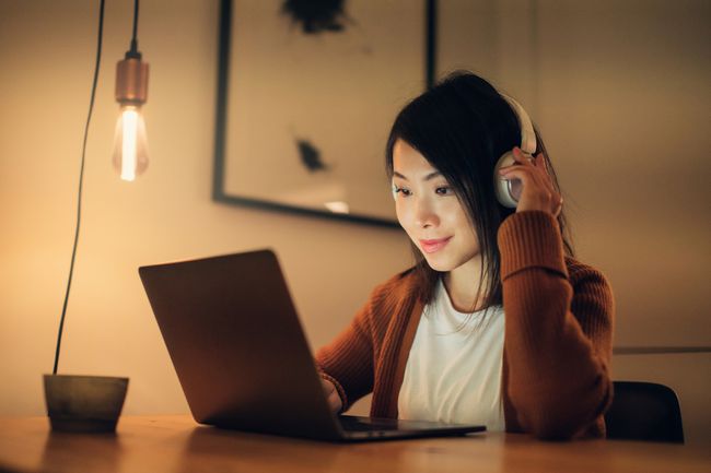 Nainen kuuntelee musiikkia MacBookilla