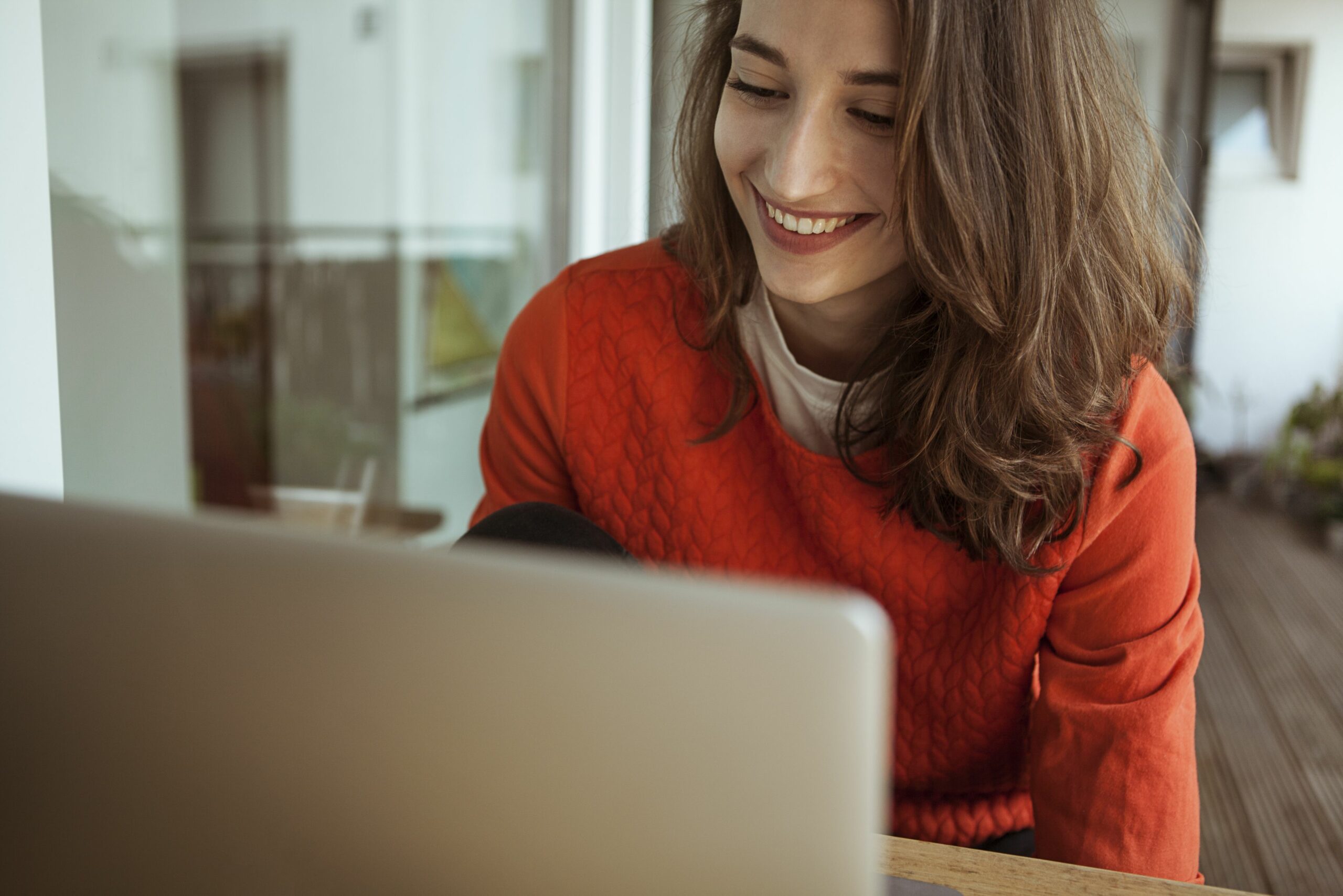 smiling young woman using laptop on balcony 900250042 5bfdc2d946e0fb0026a708d5 scaled