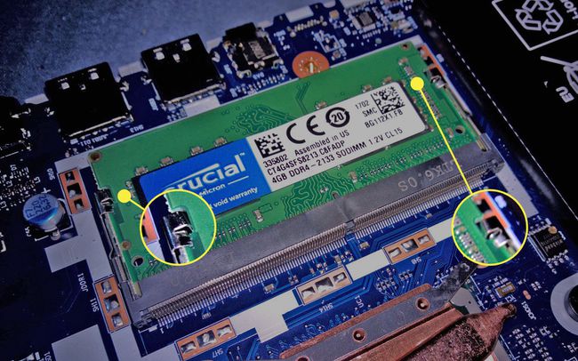 Kiinnikkeet, jotka kiinnittävät DIMM-muistin kannettavan tietokoneen emolevyyn.
