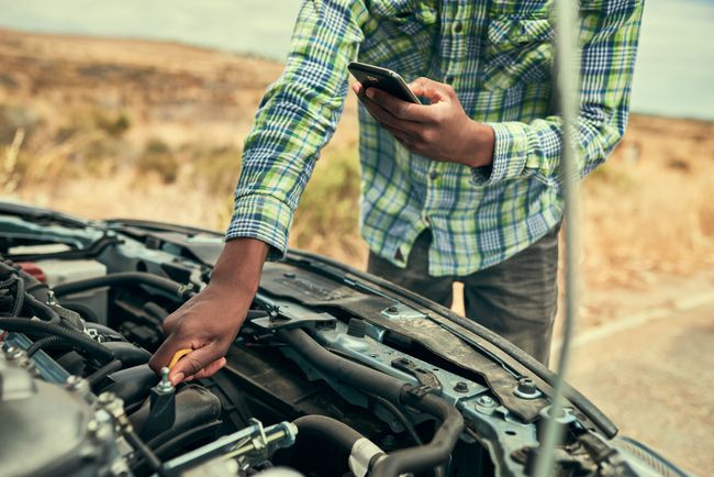 Henkilö, joka käyttää diagnostiikkatyökalua autossa konepellin ollessa auki