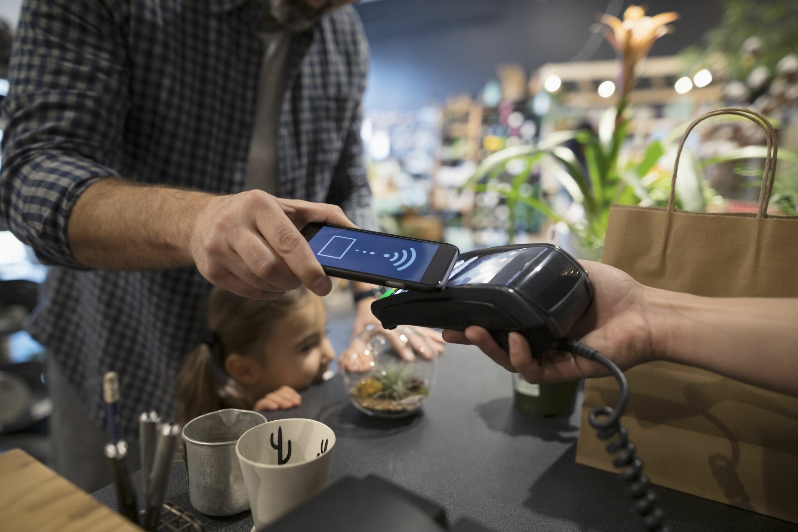 close up father and daughter paying with smart phone contactless payment at plant shop counter 697537221 5b2d60593037130036fa61c0 scaled