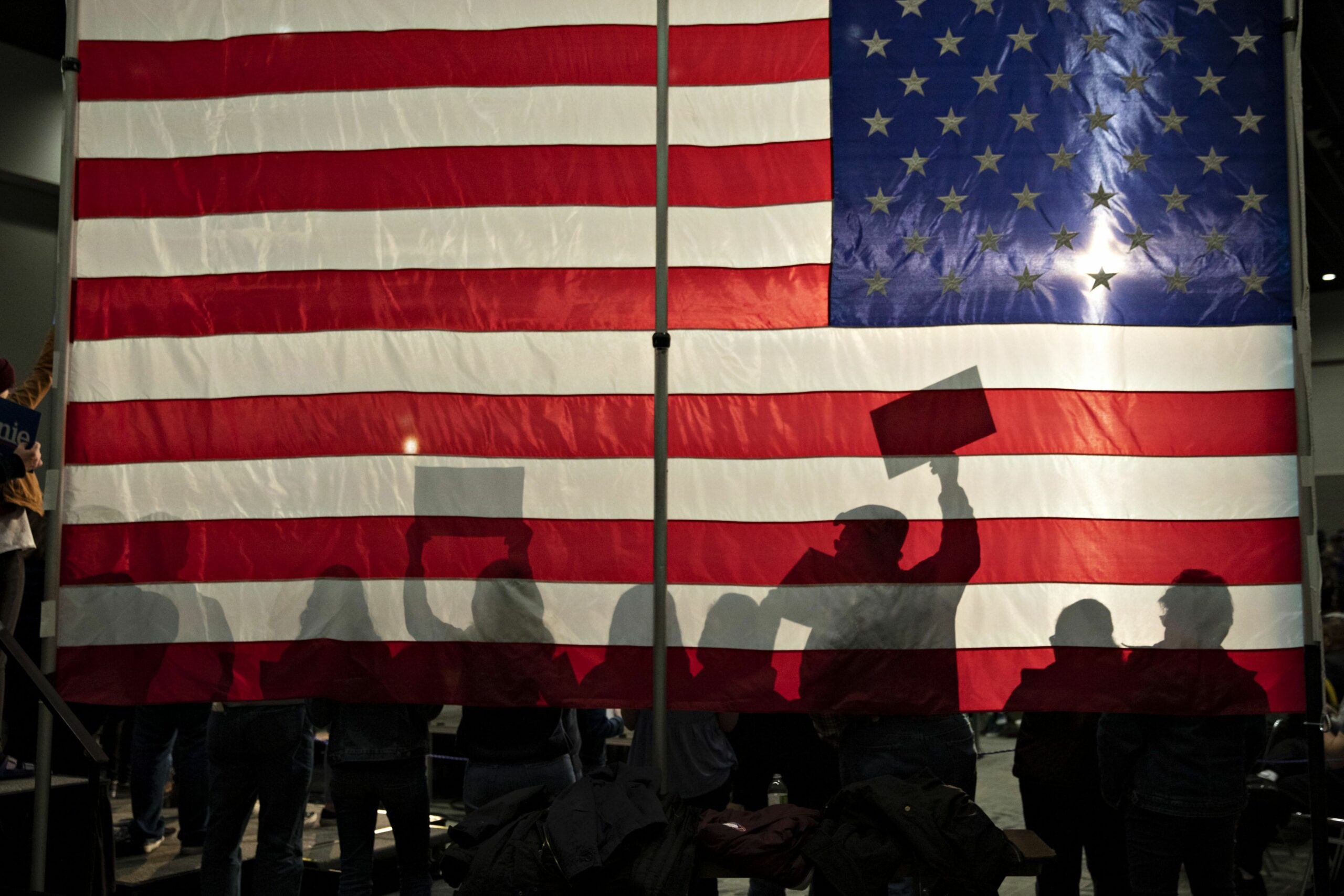 people silhouetted against an american flag 1214707683 405991a5634c4e6b976c66b0a1019a09 scaled