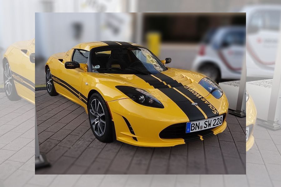 Varhainen keltainen Tesla Roadster mustilla raidoilla.