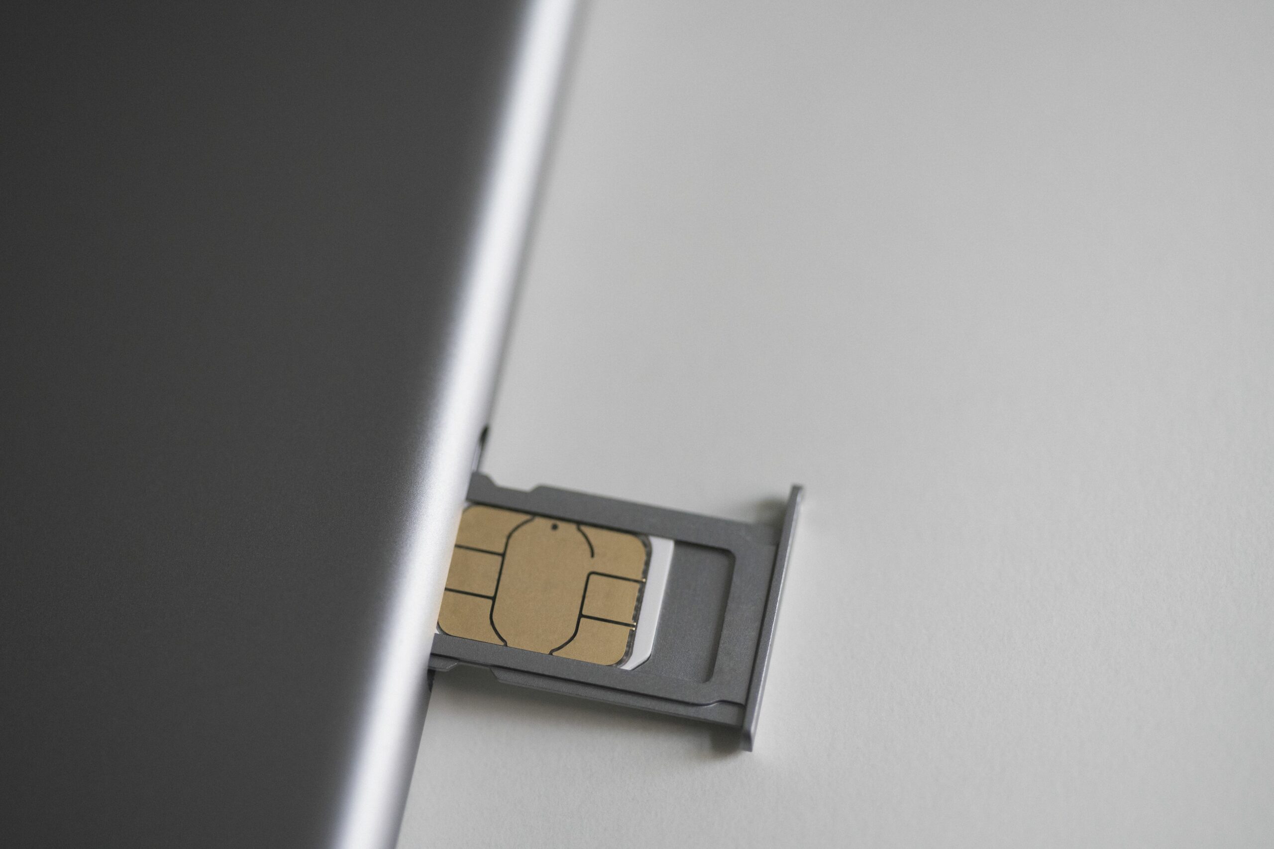 close up of sim card and mobile phone on white table 743692241 5c4cc359c9e77c0001f321e7 scaled