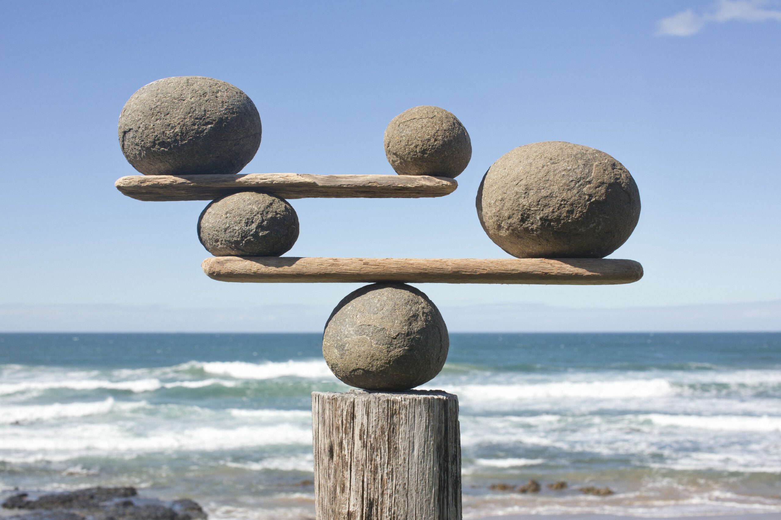 rocks balancing on driftwood sea in background 153081592 591bbc3f5f9b58f4c0b7bb16 scaled