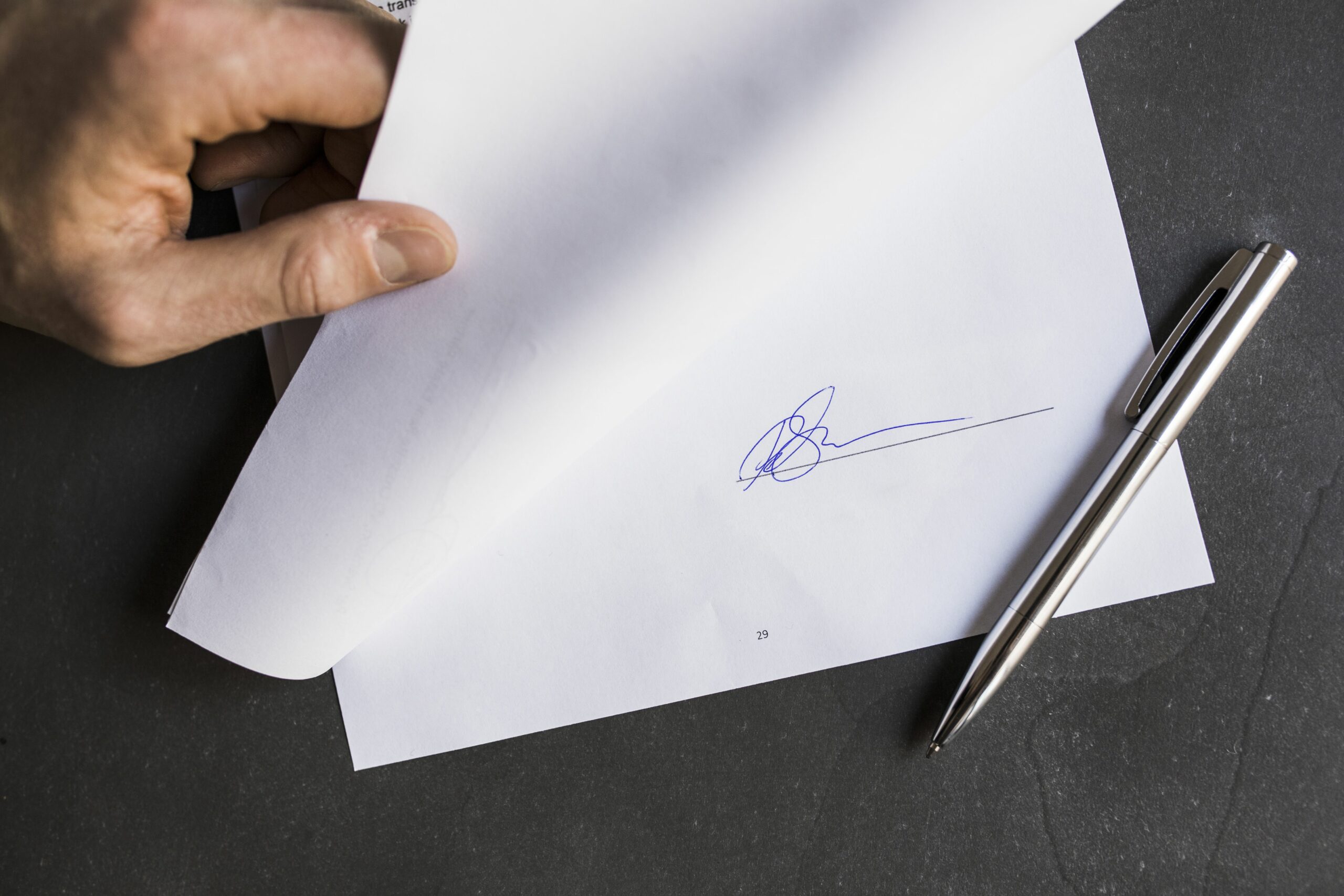 cropped image of businessman holding document with signature 723515191 593defc85f9b58d58a33d3ad scaled