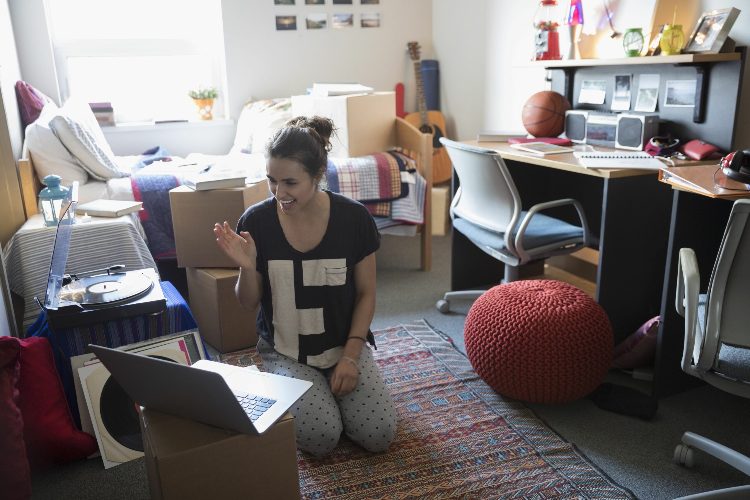 female college student waving video chatting with laptop in dorm room 736491789 5ae9bd2bae9ab80037a93138 scaled