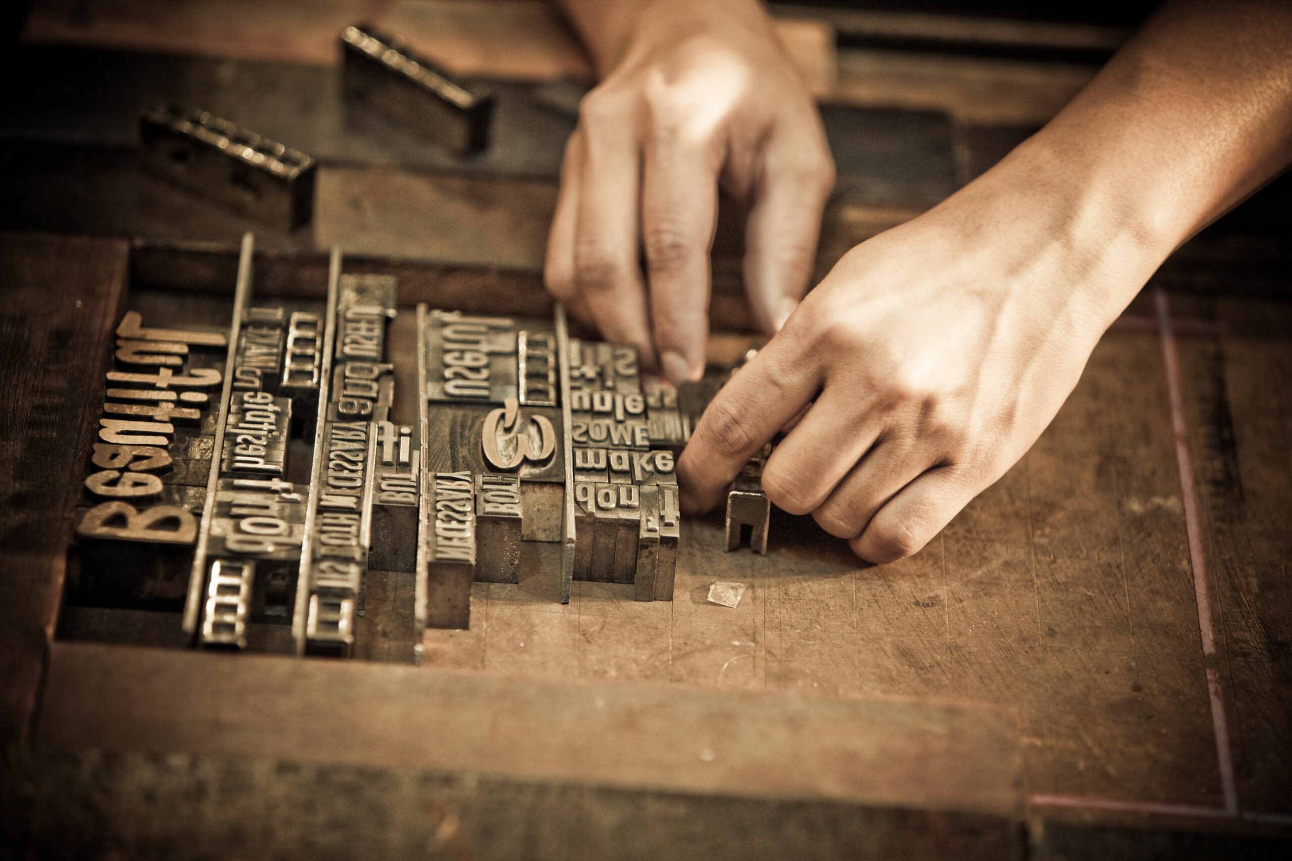 a pair of hands arrange letters for letterpress 103005733 5a1ddbc7c7822d001a96758b scaled