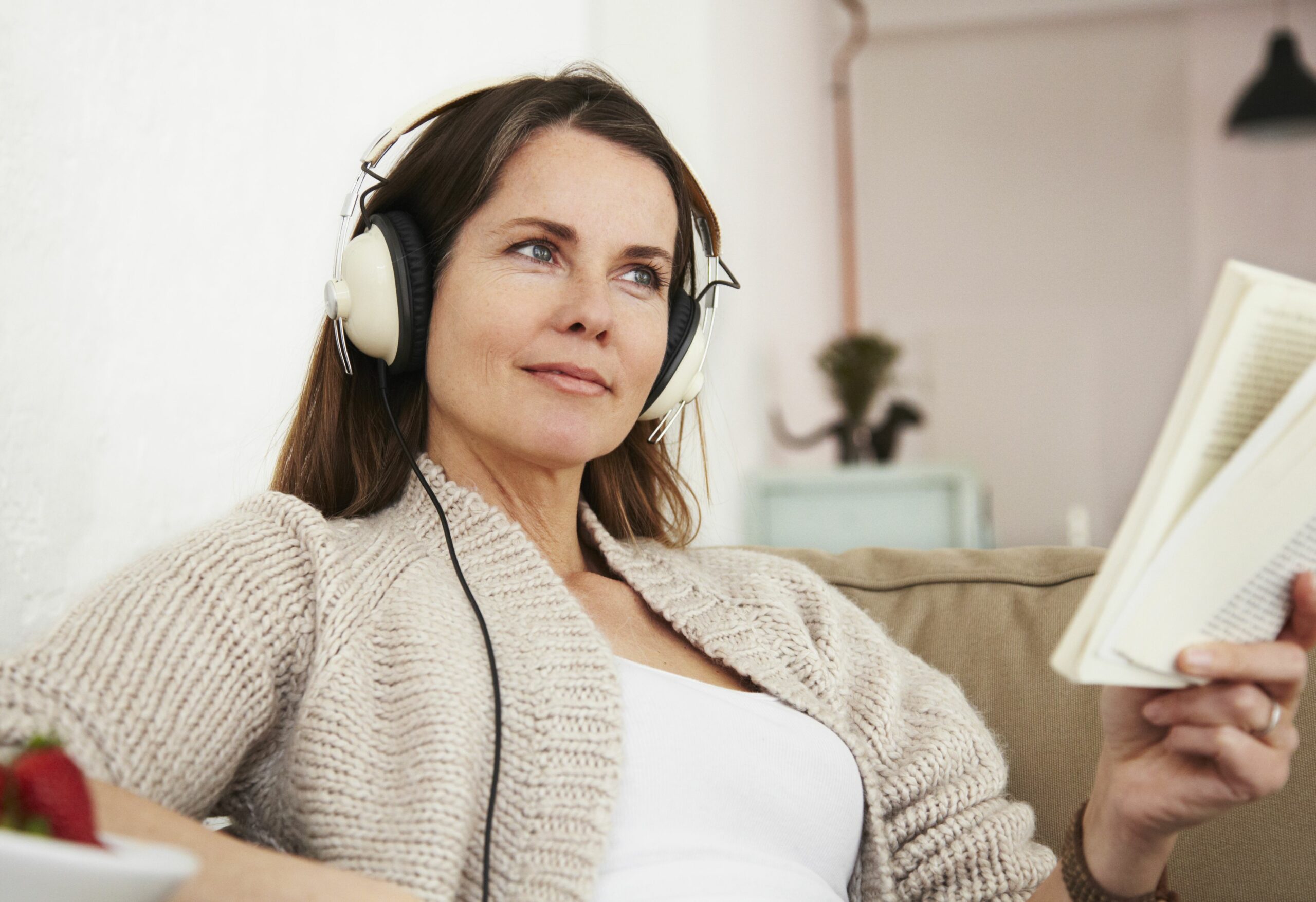 middle aged woman sitting on sofa listening to music and reading book 535257292 5b30f3eb0e23d900368df0c0 scaled