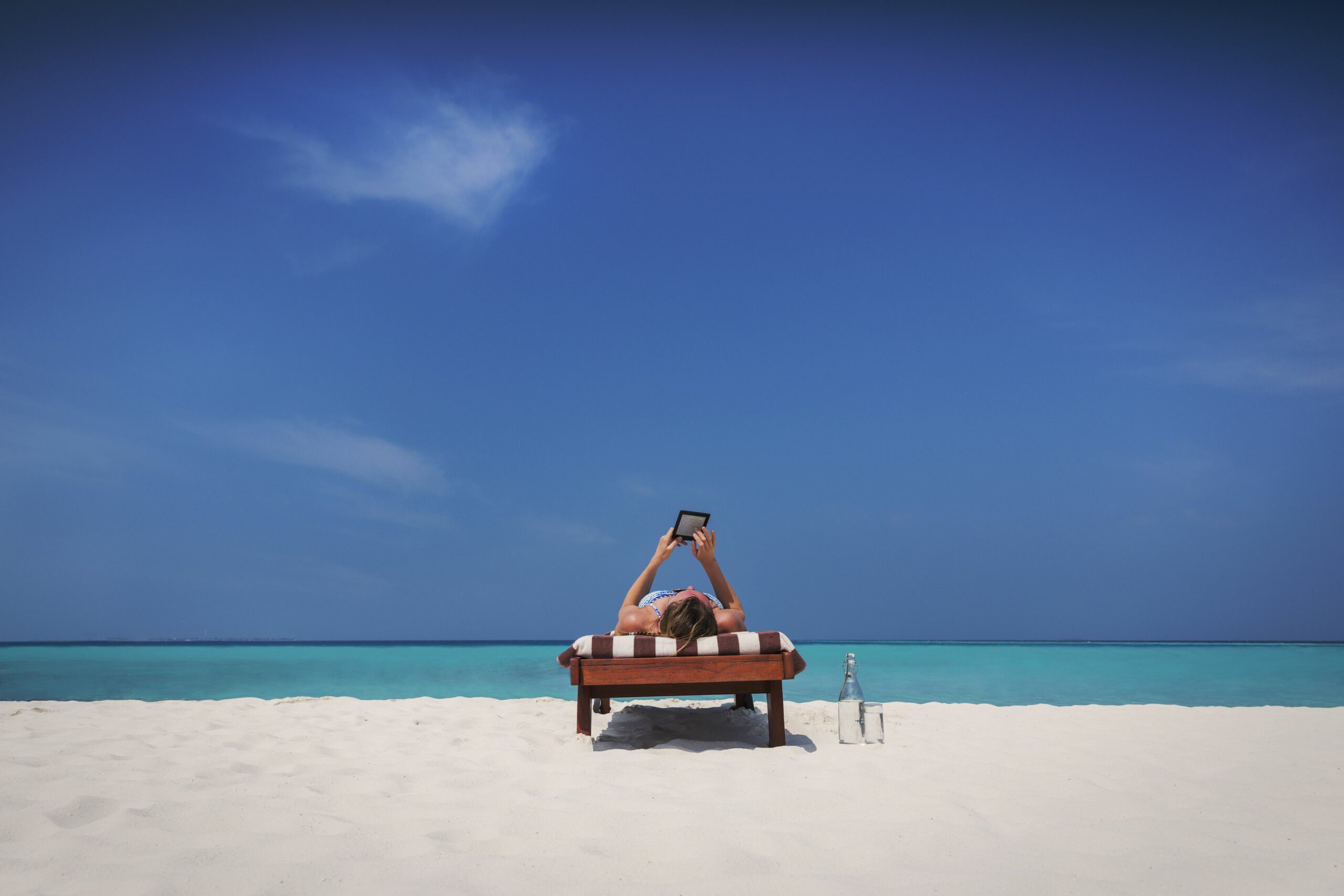 woman relaxing sunbathing laying on lounge chair and using digital tablet on sunny tropical beach 730132809 5b183367ff1b780036d7fd5b scaled