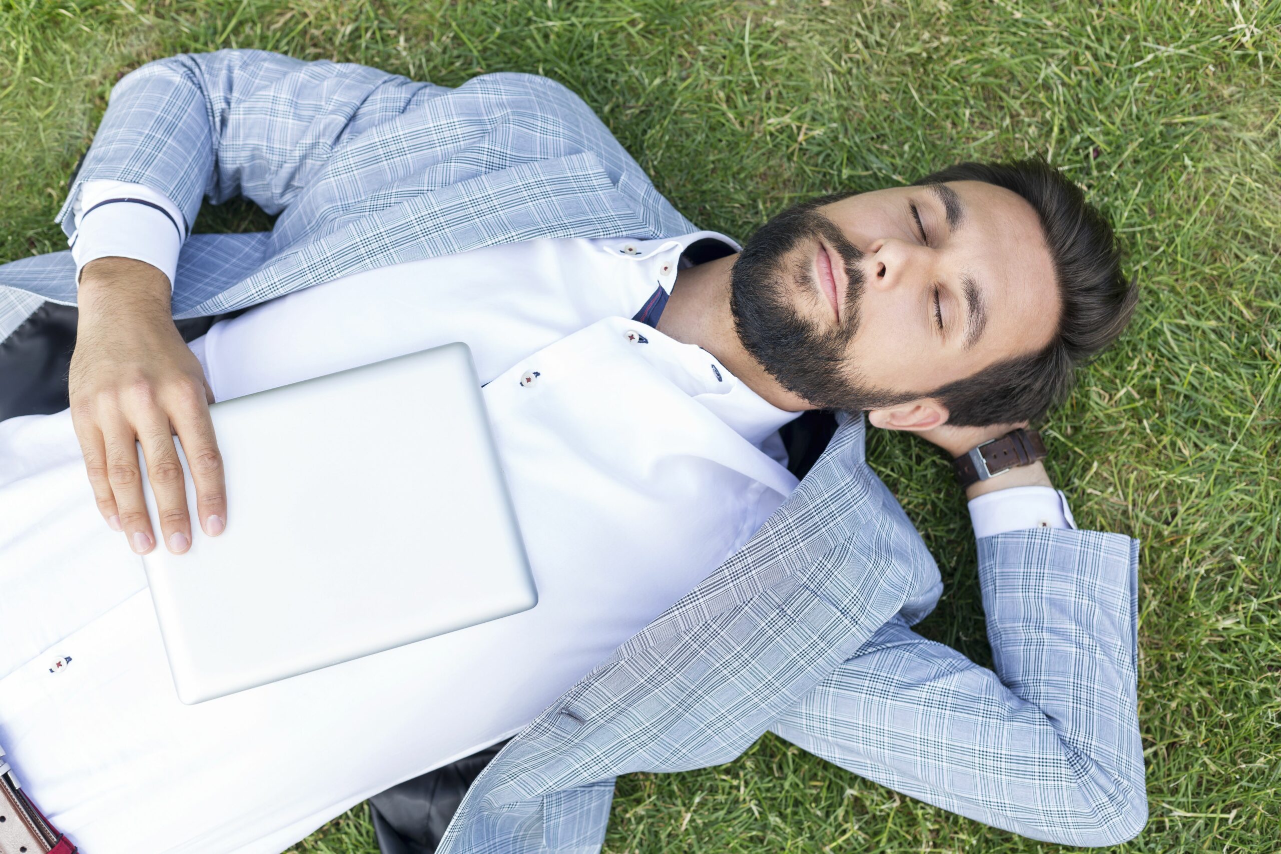 man lying on lawn with closed eyes holding digital tablet 590773539 5b47a26a46e0fb00549a0009 scaled