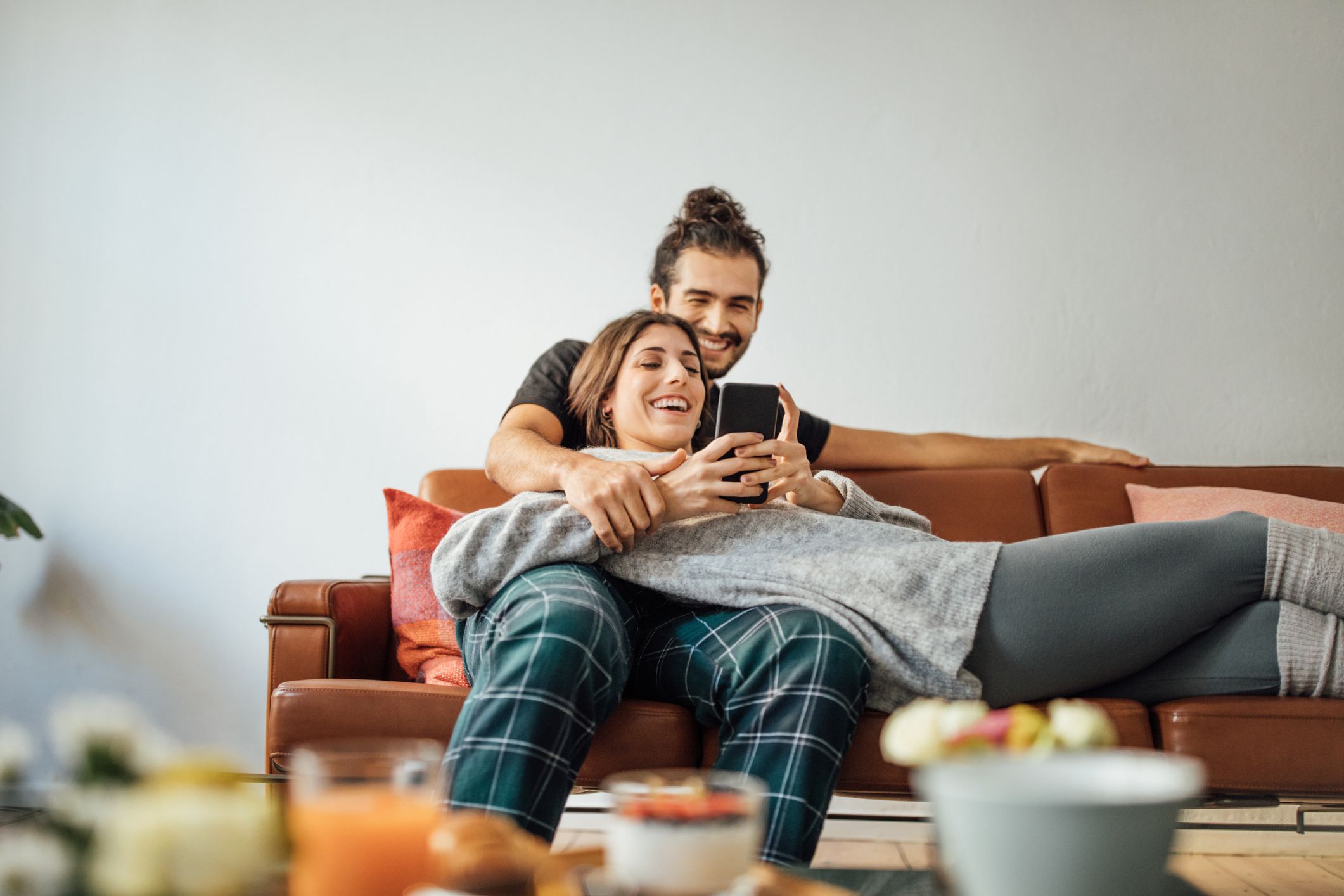 young couple with smart phone relaxing on sofa 974230862 5c4b4d5ec9e77c00013801fc