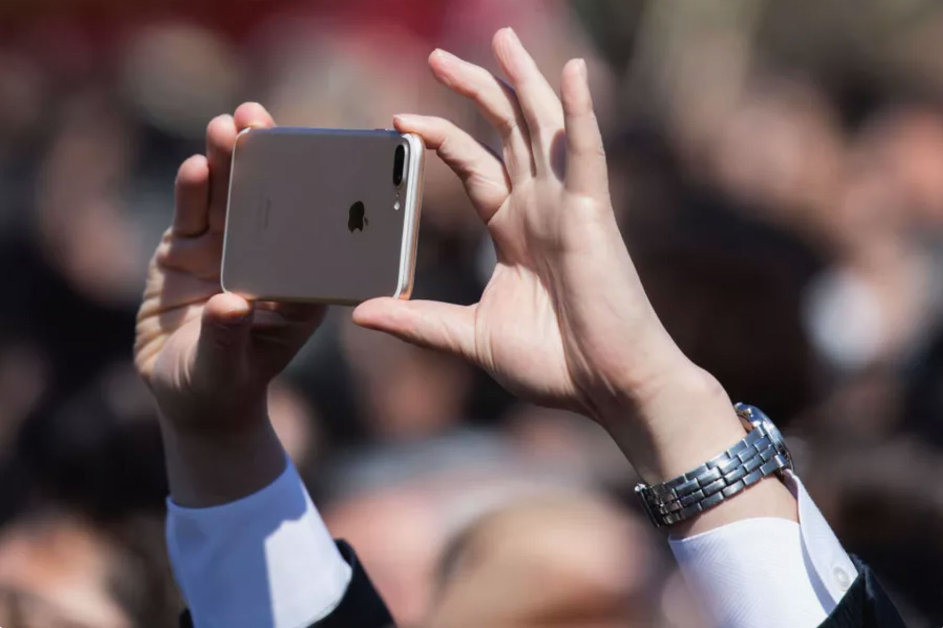 Henkilö pitelee iPhonea valokuvan ottamiseksi