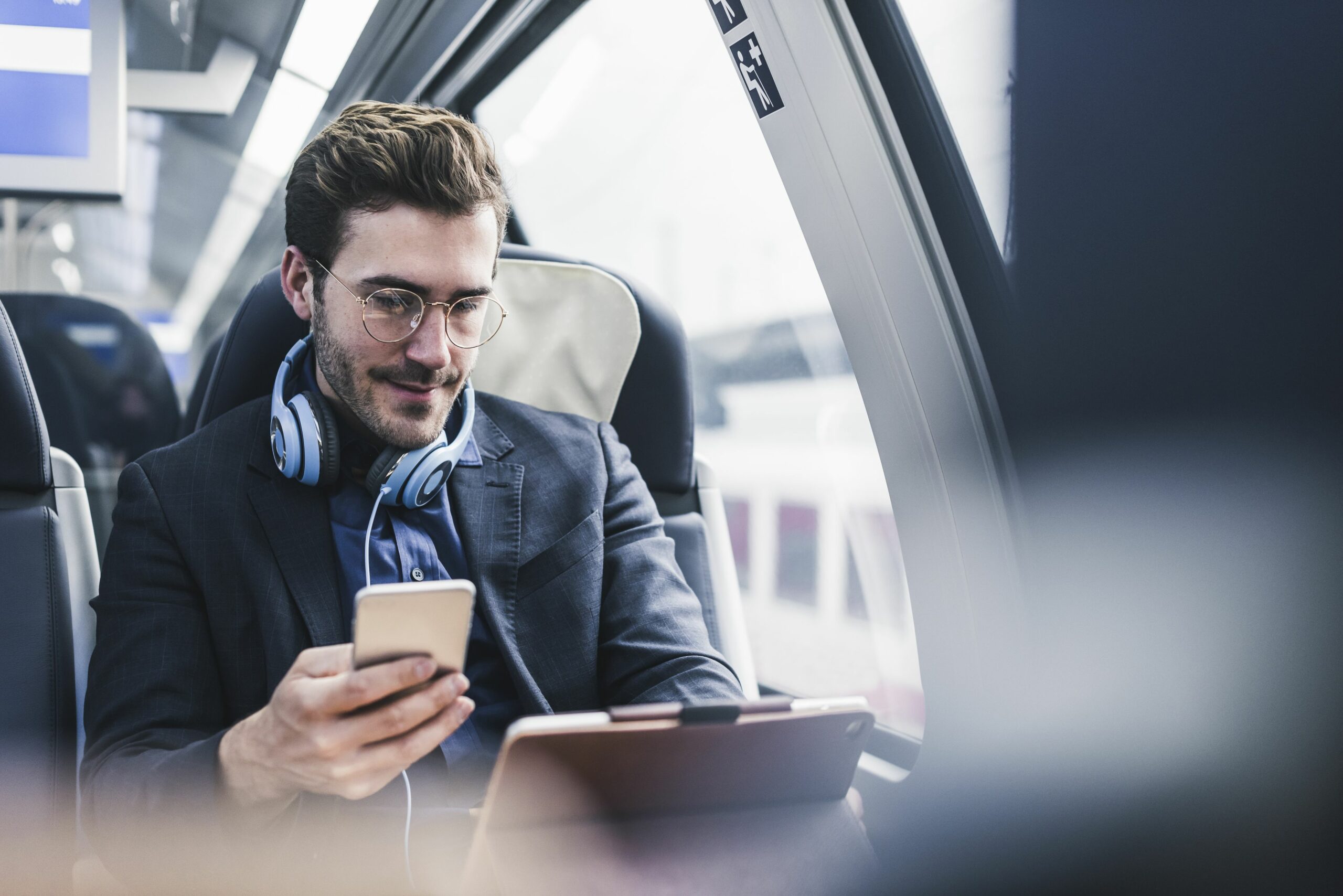 businessman in train with cell phone headphones and tablet 932633170 5b9e7c58c9e77c0050941bea scaled