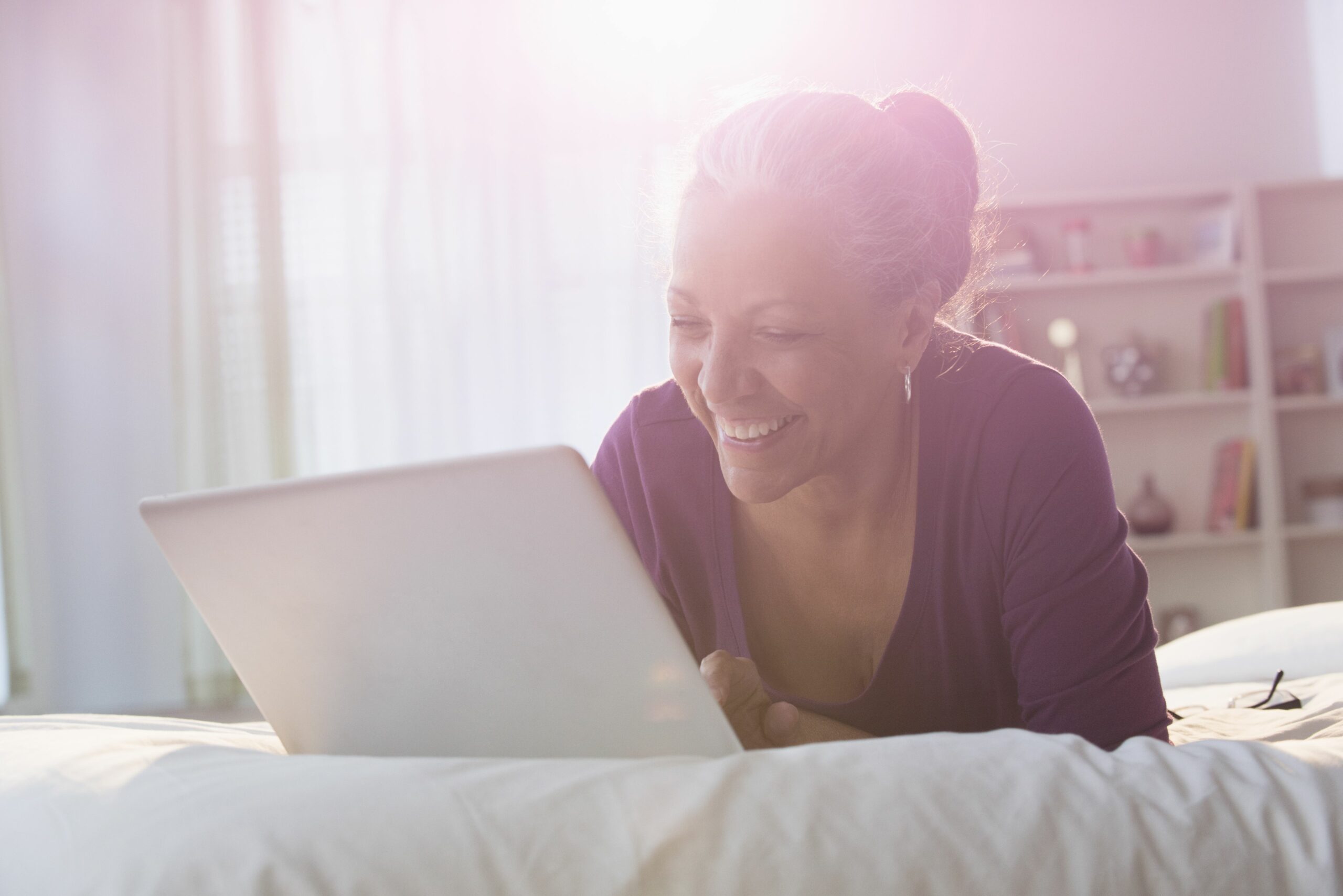 older hispanic woman using laptop on bed 546825877 59bdb77ac4124400106d23cd scaled