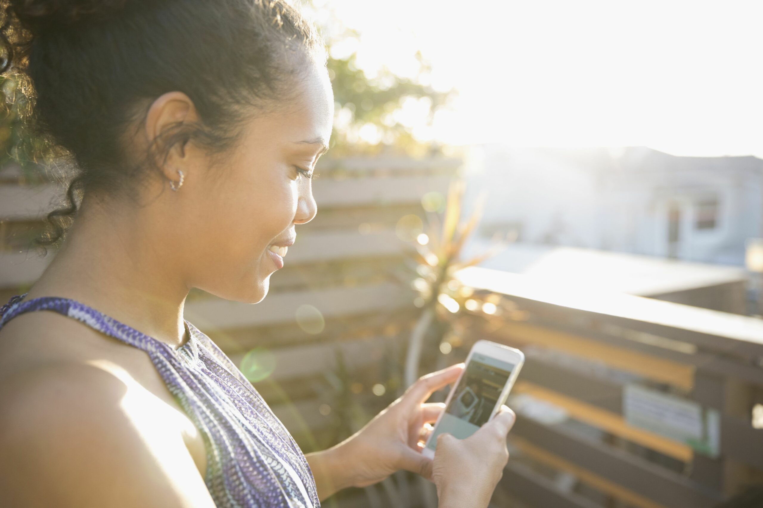 woman using smart phone on sunny deck 719875919 59d7de9868e1a20010221f6a scaled