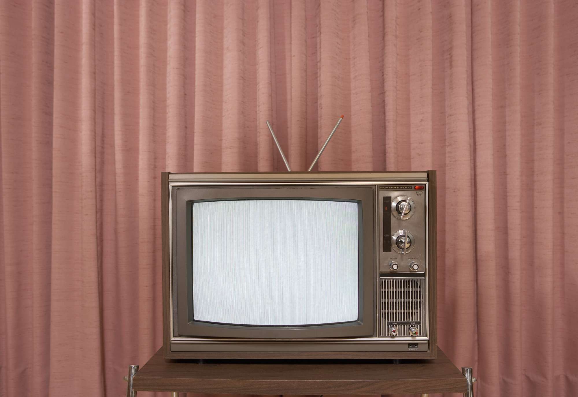 Vanha televisio jalustalla, verhon edessä