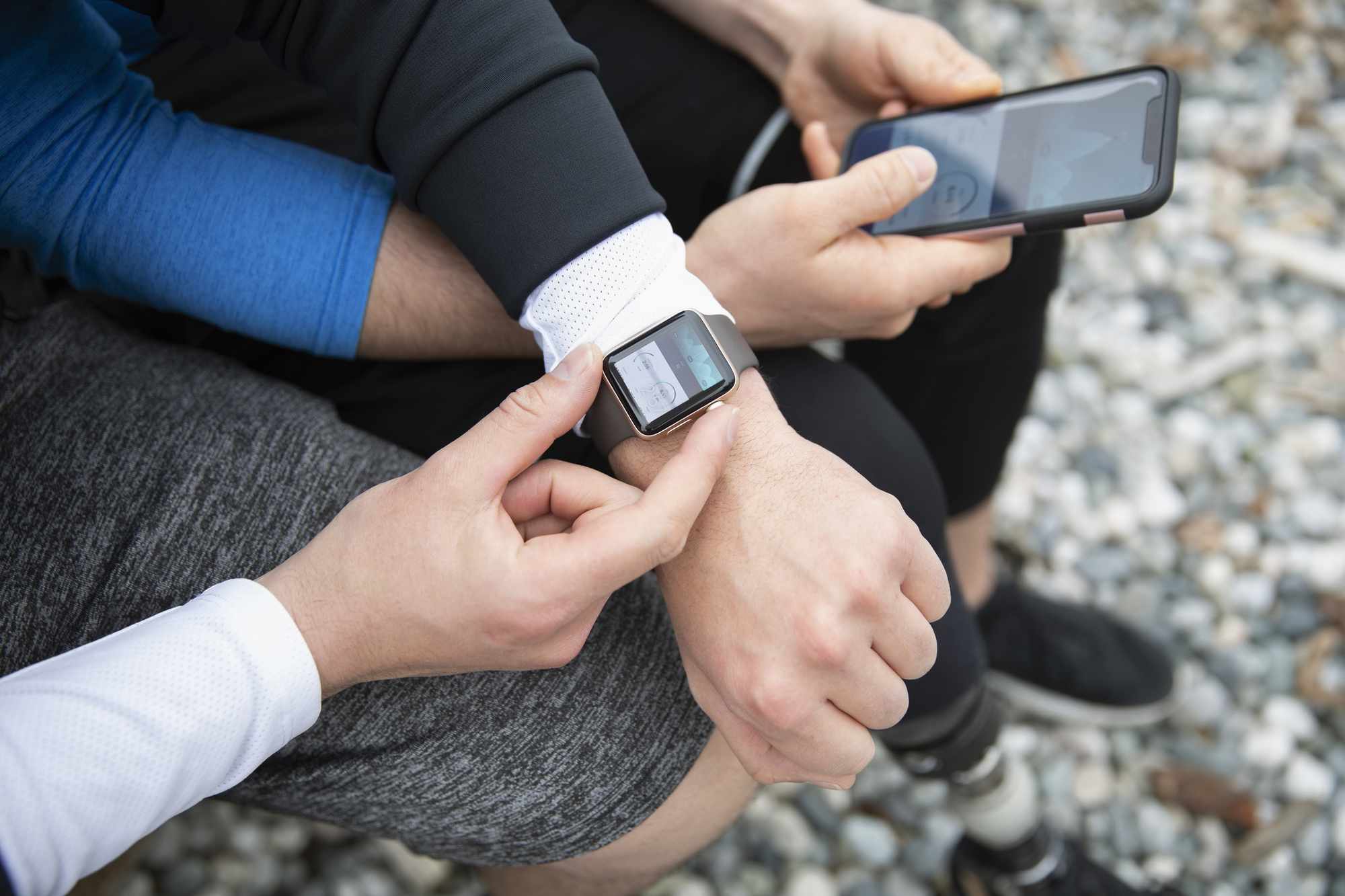 Pari juoksijaa katselemassa Apple Watchia ja iPhonea