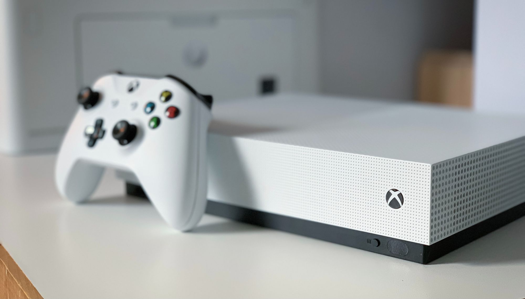 Valkoinen Xbox One -konsoli, jossa valkoinen ohjain nojaa sitä vasten.